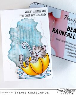 Hello crafty friends. Sylvie @kaliscards here with a fun rainfall card with the new @pearblossompress kit. If you've created rainfall cards before, you know they are a bit of work and the kit makes it so easy and much faster. First of all, it contains everything that you need in a pretty metal tin with a die that creates the rainfall thread guide for you. The kit also has a beautiful choice of seed beads with a silver lining, thread and needles, foam tape strips and detailed instructions!

Products:
Beaded rainfall kit (Pear Blossom Press)
Tunnel clouds dies (Spellbinders)
March cat (Pink and Main)
Over the rainbow sentiments (Sunny Studios)

#pearblossompress #pinkandmain
#cardmaking #interactivecard