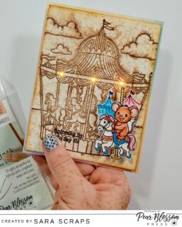 @sara.scraps is spinning by to say hi with this adorable interactive card on our You Tube channel today. Her neutral background with its painterly  feel is the perfect background for her stamped image! And those EZ Lights add the perfect addition to her card, adding a fun element to her carousel background. Be sure to check out her video for all the fun details! #handmadecrafts #cardmaking #pearblossompress